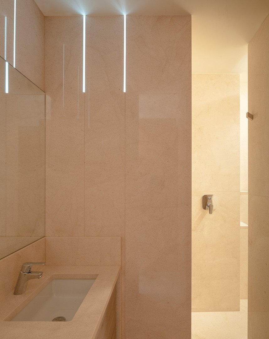 Baño del apartamento de piedra con lavabo de piedra y luz entrando por una hendidura