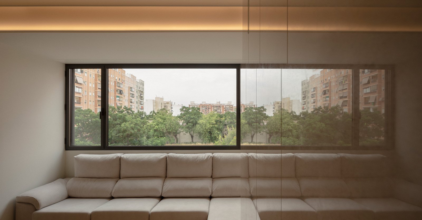 Salón del apartamento de piedra con sofá corrido y ventanal