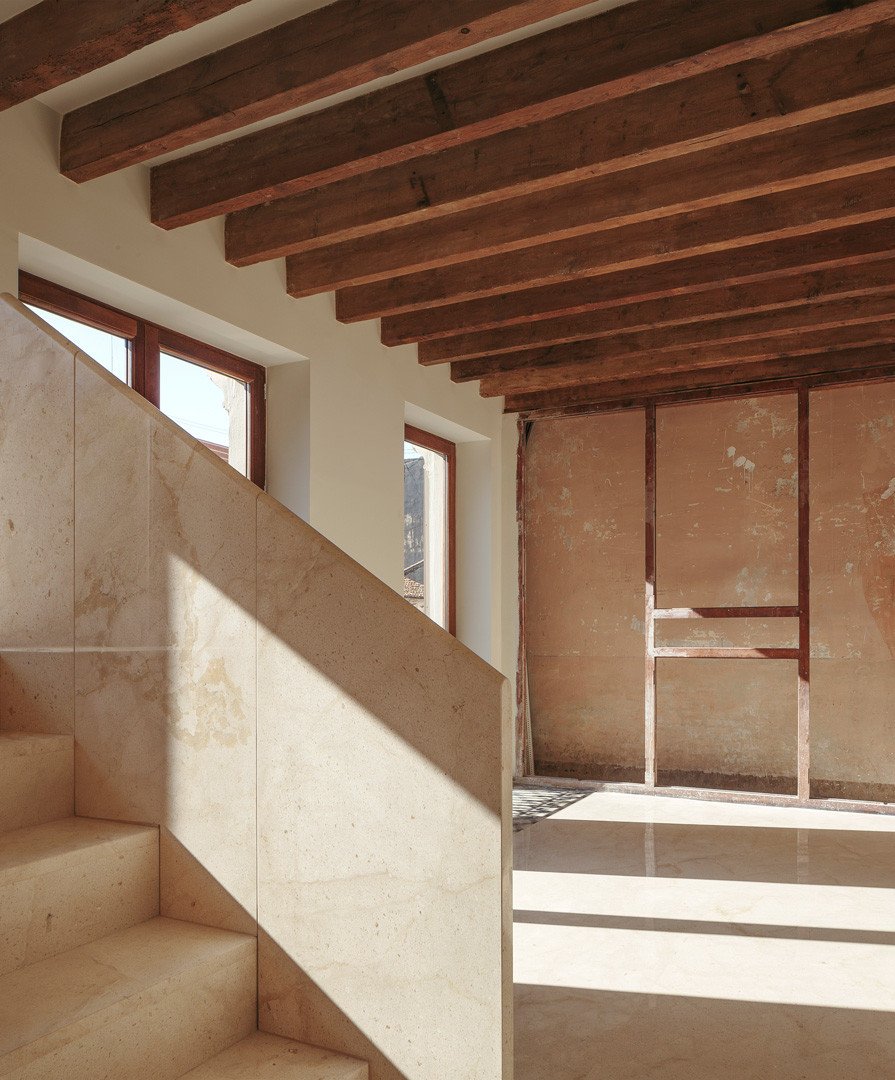 Escalera de piedra bajo el techo de viguetas de madera, frente a un muro original conservado en la Casa de los Gigantes
