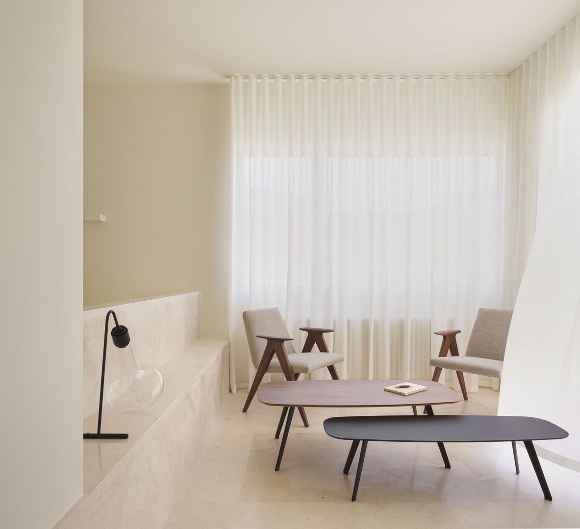 Sala superior de la Casa del Limonero con sillones, mesas bajas y cortinas
