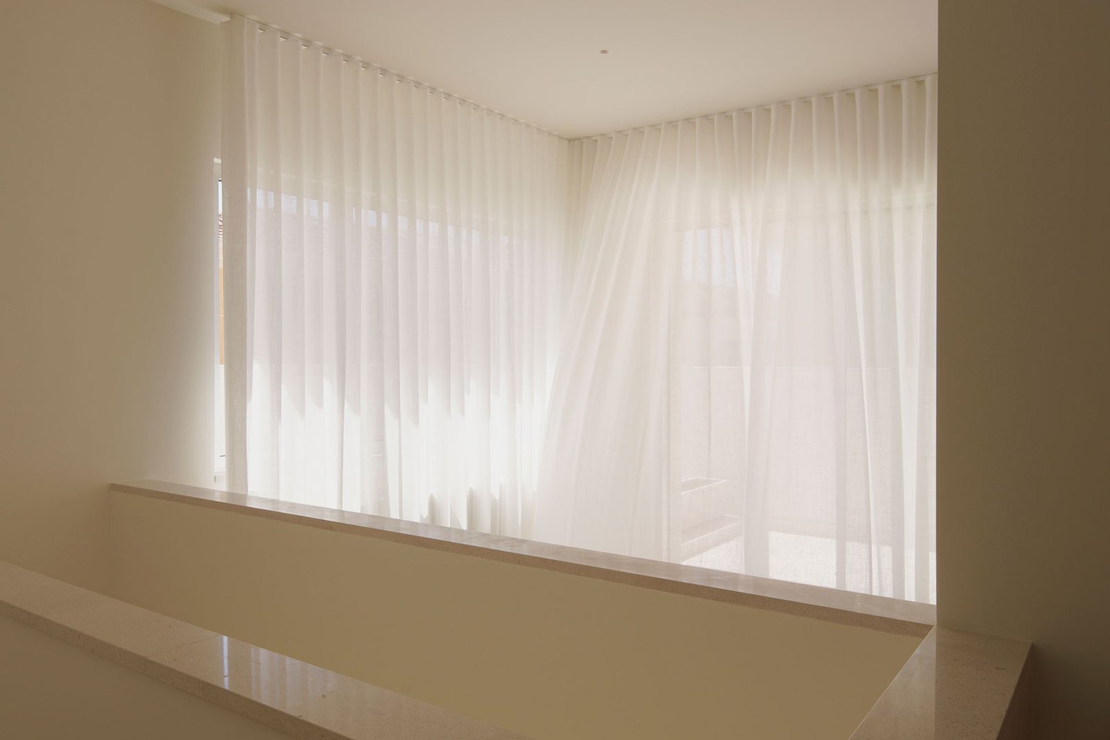 Banco corrido bajo la ventana con cortinas en la planta primera de la Casa del Limonero
