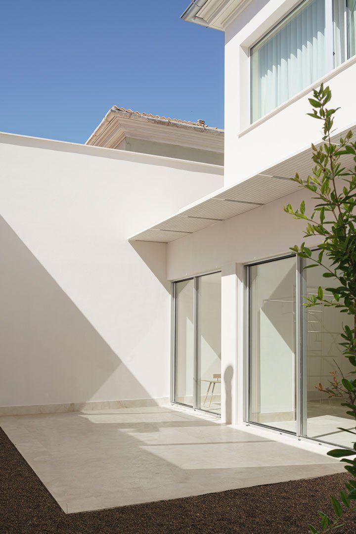Patio trasero de muros blancos y ventanales de la Casa del Limonero