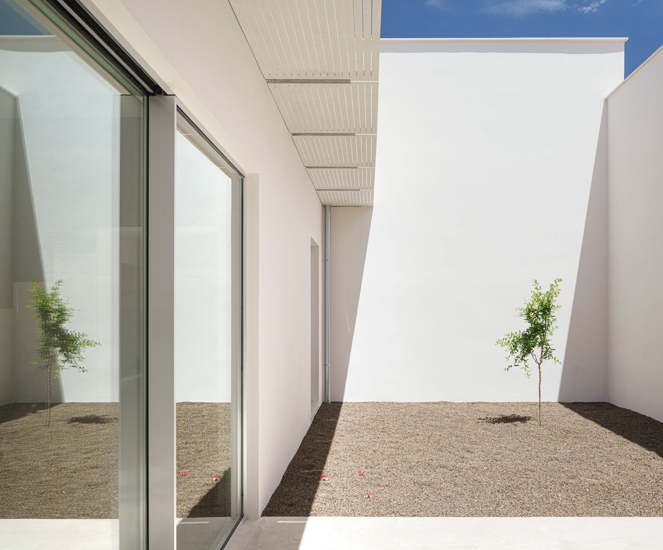 Patio trasero de muros blancos y suelo de greda volcánica visto desde el interior de la Casa del Limonero
