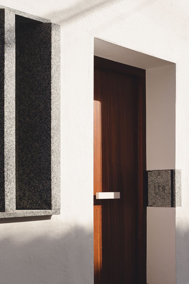 Entrada de Casa Mirasol con puerta de madera, celosía y buzón de granito