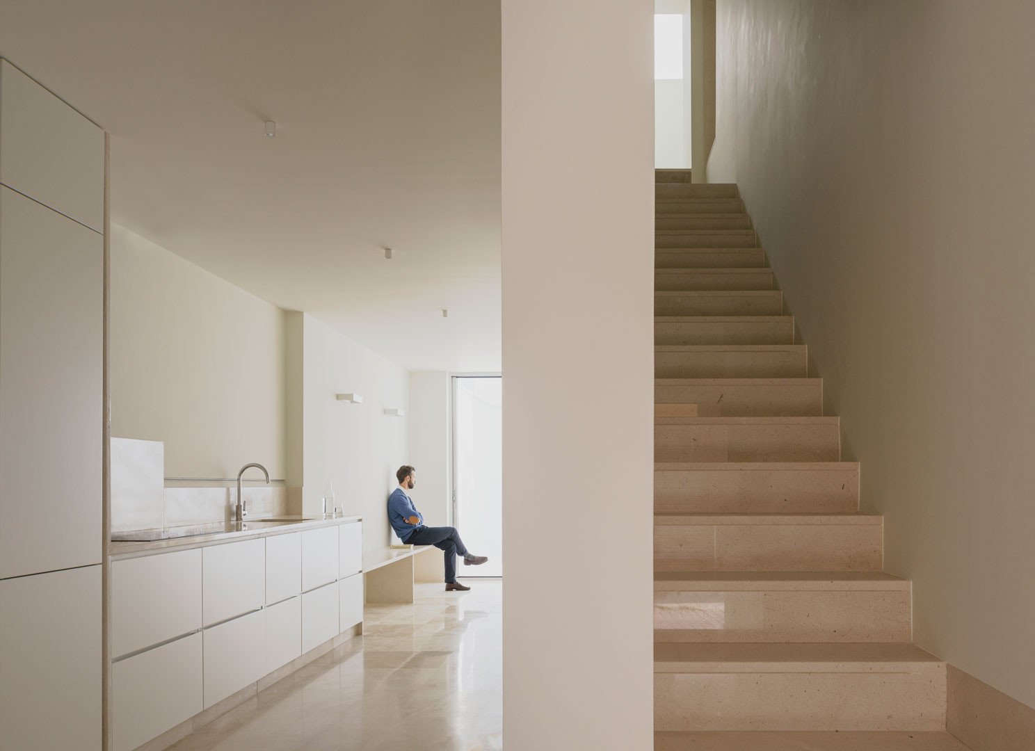 Escalera de piedra caliza y estancia de planta baja de Casa Mirasol, con una persona sentada