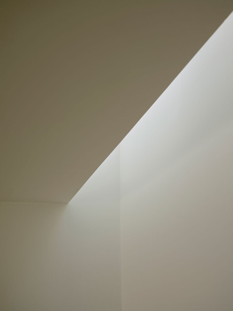 Luz diagonal sobre los muros enlucidos en cal del interior de Casa Nido