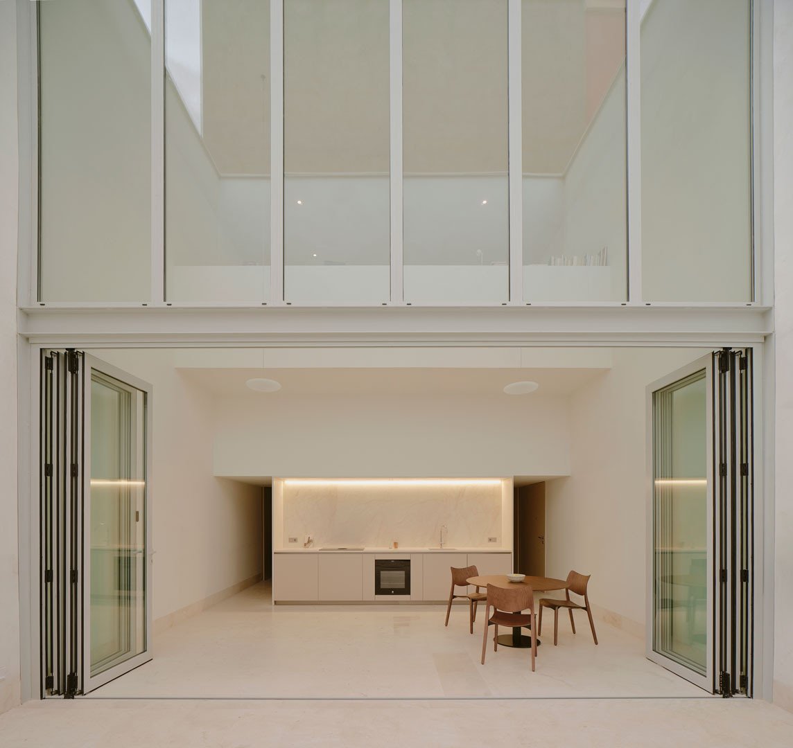 Espacio continuo en doble altura de Casa Nido, de la cocina al patio, con la planta superior sobre él