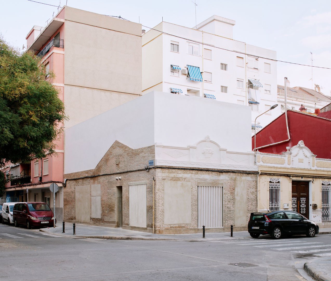 Vista de Casa Nido desde la esquina de la calle, con el volumen enlucido en cal sobre las antiguas medianeras