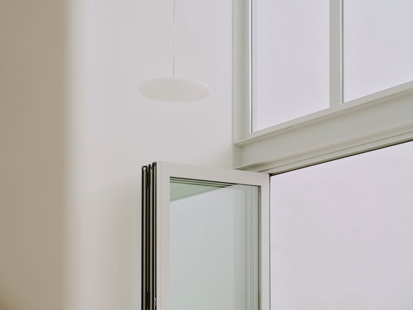 Detalle de la carpintería de la ventana en doble altura de Casa Nido, con luz sobre el muro