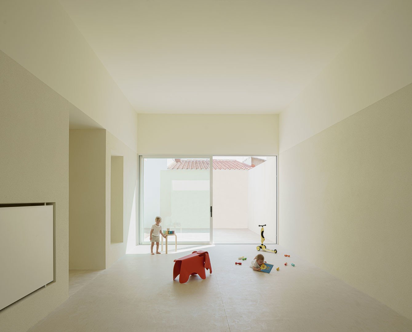 Sala de gran altura entre dos patios de la Escuela en Aguas Nuevas, con niños al fondo