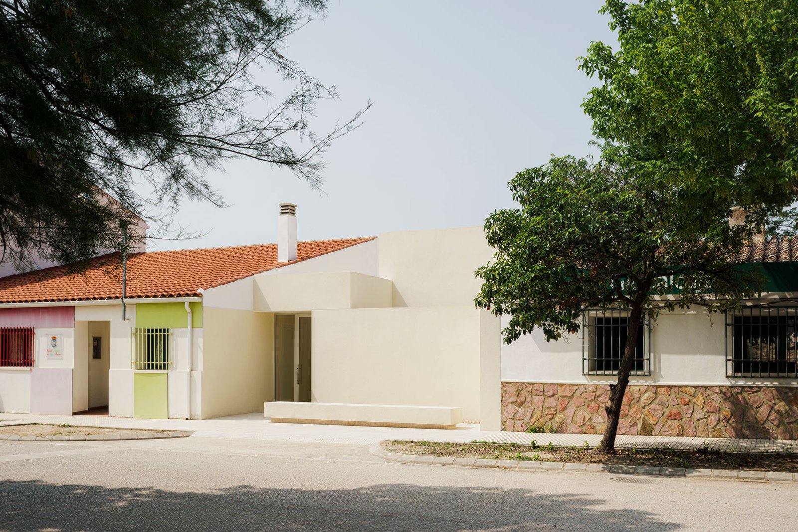 Escuela en Aguas Nuevas vista desde la calle, entre arbolado y arquitectura doméstica de baja altura