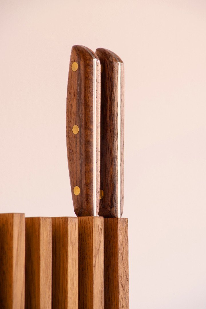 Mangos de dos cuchillos emergiendo de las fundas de madera de Petra