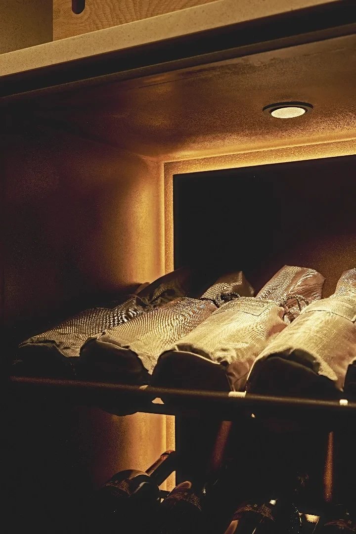 Nichos de piedra caliza iluminados con botellas de vino en Tinta